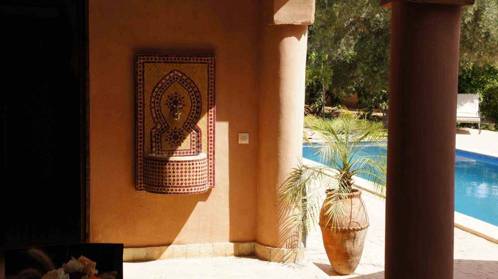 Galerie couverte et fontaine murale donnant sur la piscine du riad