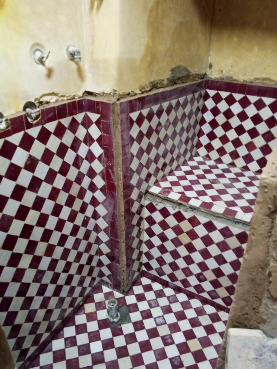 Pose de zellige rouge et blanc dans une salle d’eau de riad