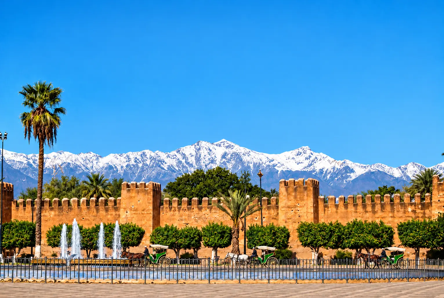 Visuel de Taroudant avec remparts, montagnes enneigées, palmiers et trois calèches.